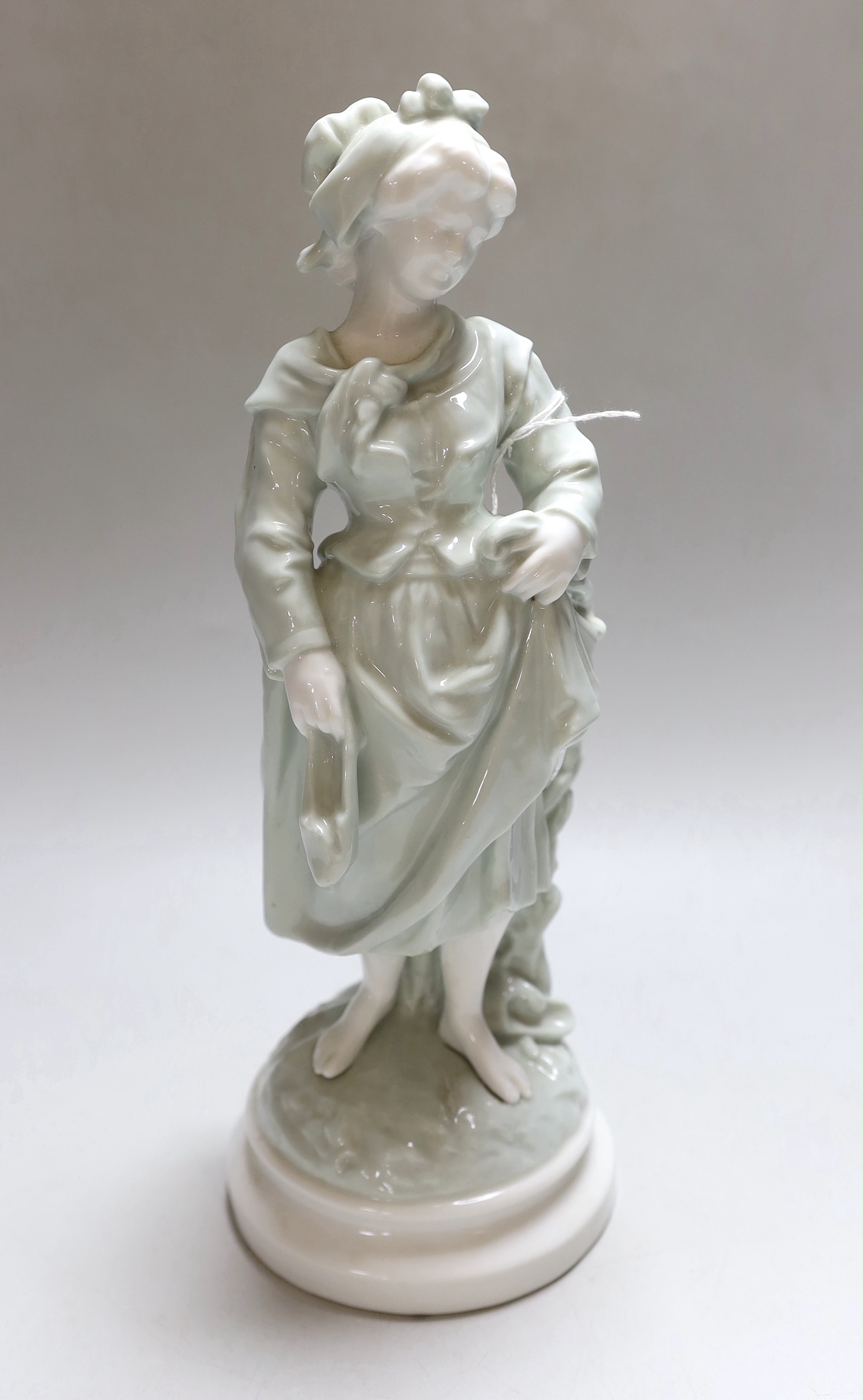 A celadon glazed figure of a girl, barefooted beside a tree, holding her skirt off the ground, c.1885-90, 32cm high